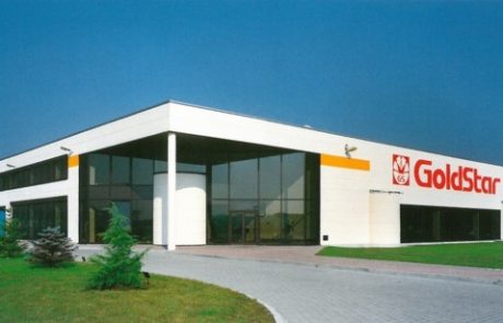 Moderne Firmengebäude-Architektur mit großen Fenstern und dem Logo von GoldStar an der Fassade unter klarem Himmel.