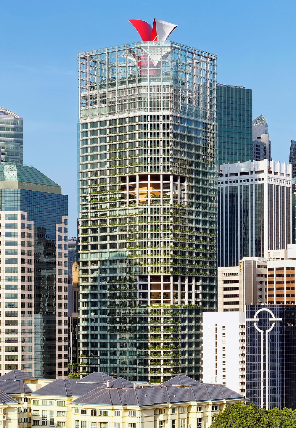 Modern high-rise façade with vertical gardens, surrounded by other skyscrapers under a blue sky.