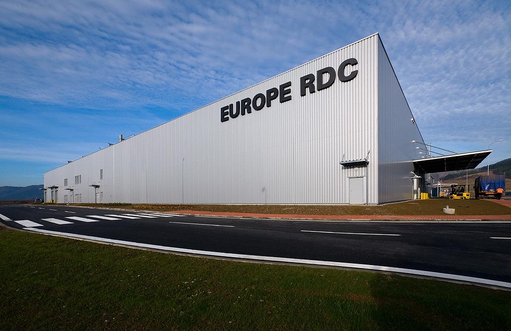 Großes Industriegebäude mit der Aufschrift "EUROPE RDC" an einem sonnigen Tag, straßenseitig gelegen, mit klarem Himmel im Hintergrund.