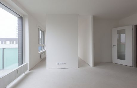Modern interior design of an empty office with white walls, floor-length windows and light carpet. Glass door leads into adjacent room.