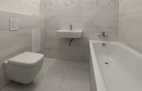 Modern bathroom with light tiled walls, floating toilet, wall-mounted sink and built-in bathtub. Elegant and minimalist design.