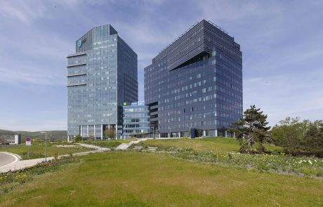 Moderne Glasfassade-Bürogebäude im Lakeside Park mit Grünflächen im Vordergrund bei klarem Himmel.
