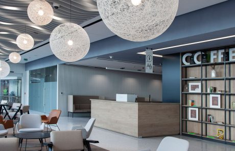 Modern gestaltete Bürolounge mit hängenden runden Leuchten, Empfangstheke und gemütlichen Sitzgelegenheiten.