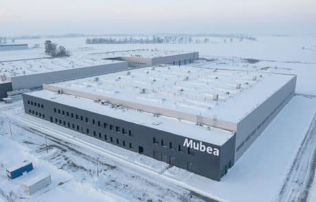 Industriekomplex von Mubea im Winter, flache Bauweise mit Firmenlogo, schneebedecktes Dach und Umgebung, moderne Architektur.