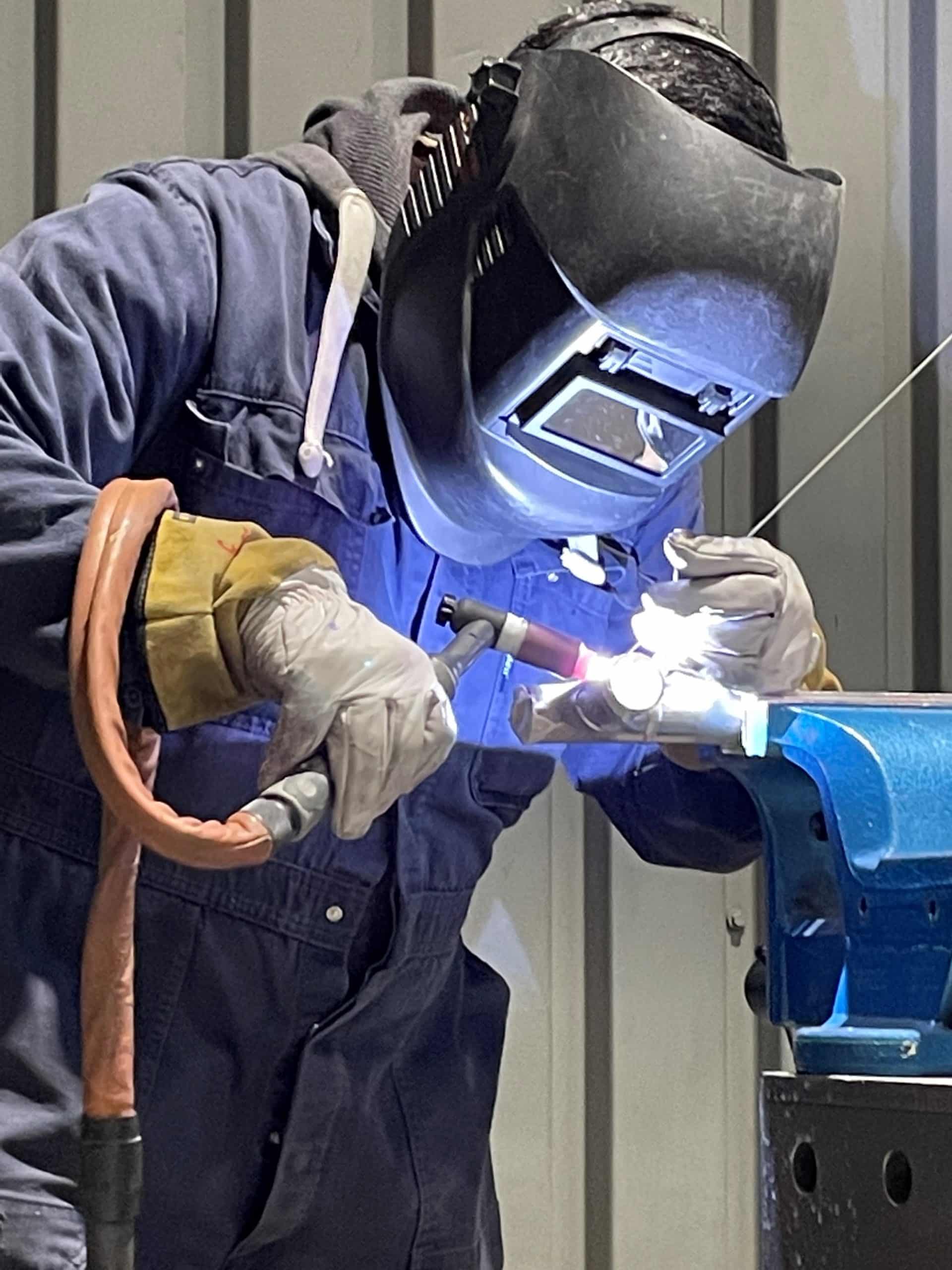 Welder in protective equipment carries out welding work with a bright arc.