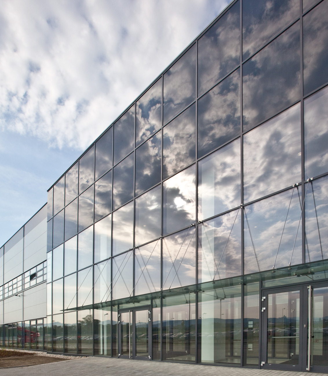 Stunning reflection of clouds on the glass façade of the Alps office building's entrance in Slovakia – a construction project by Takenaka.