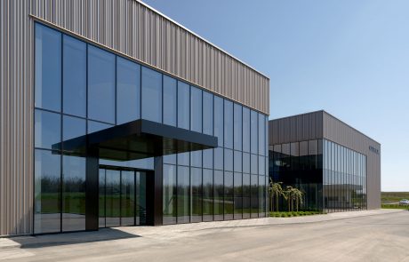 Seiren building: Modern company headquarters with large glass fronts and metallic façade, framed by a paved forecourt and green strip.