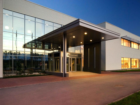 Modernes Bridgestone Fabrikgebäude bei Dämmerung mit reflektierenden Fenstern und beleuchtetem Eingangsbereich.