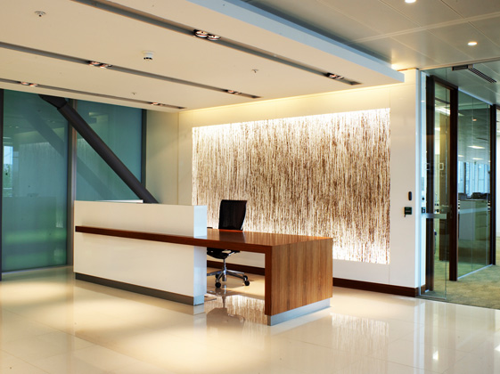 Moderner Büroraum mit Rezeptionstresen, Kunstinstallation an der Wand und Glaswänden im Hintergrund.